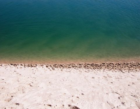 Minimalist Sandy Beach Meeting Calm Turquoise Water, Top-Down Coastal Shoreline with Footprints