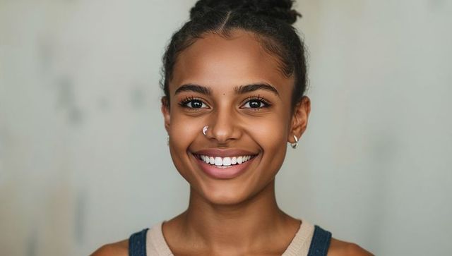 Bright smiling teen portrait with braided bun and nose ring, natural beauty headshot
