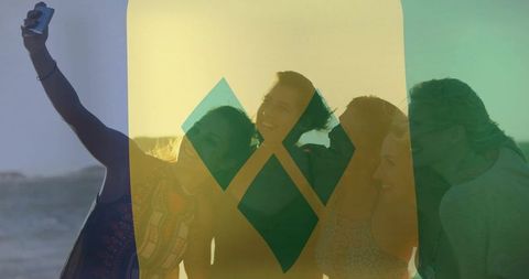 Friends taking sunset selfie on beach with warm golden-hour backlight and colorful overlay