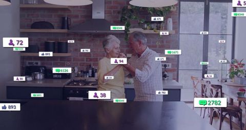 Senior couple dancing in modern kitchen with social media icons