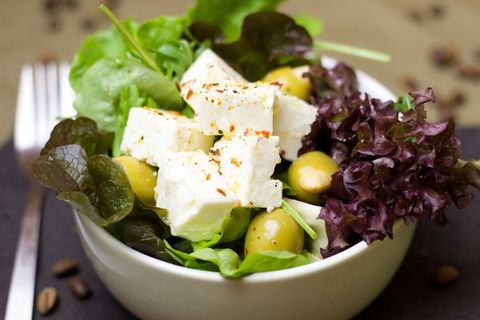 Fresh mediterranean salad featuring feta cubes, green olives and mixed baby greens
