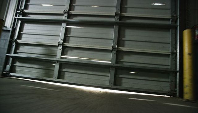 Low-angle sectional overhead garage door opening at loading dock with yellow bollard