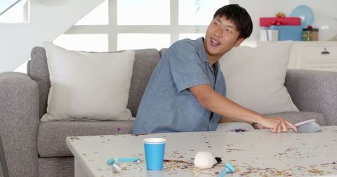Man Cleaning Confetti After Celebration at Home