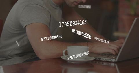 Freelancer typing on laptop with coffee cup and floating numeric data overlay in cafe