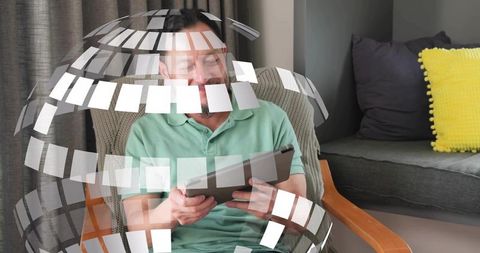 Asian man holding tablet interacting with digital globe overlay in cozy living room