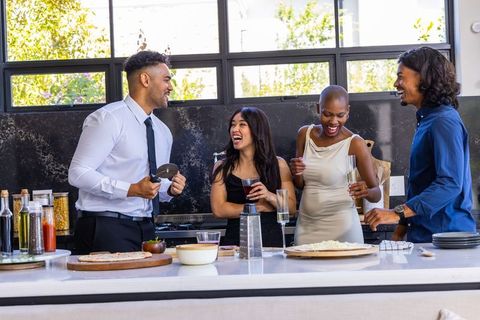 Friends laughing and serving pizza at modern kitchen island for casual home entertaining