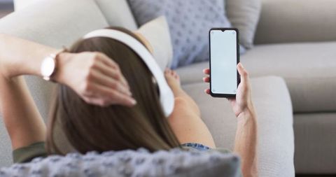Relaxing Woman with Headphones Holding Smartphone at Home