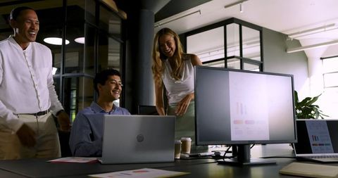Diverse Team Celebrating Success on Laptop in Modern Office