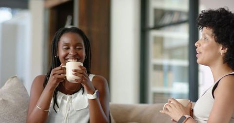 African American Women Enjoying Coffee and Conversation on Cozy Living Room Sofa