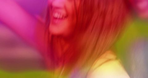 Laughing woman moving head under neon lights, motion blur and colorful light streaks