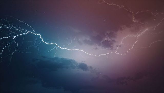 Striking lightning bolts illuminating stormy night sky