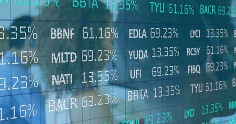 A diverse group of professionals seen through the reflection of dynamic stock market data on a glass wall, showcasing the synthesis of technology and human effort in modern finance. This image can be used to illustrate articles on investment strategies, financial analysis, or the corporate use of technology in stock trading. Ideal for websites discussing the economy, business news platforms, and financial consultancy services.