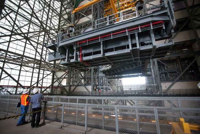 This image shows a heavy-lift crane raising the D-level work platforms for NASA’s Space Launch System rocket. The scene takes place in the Vehicle Assembly Building at Kennedy Space Center. Use this image to illustrate engineering and construction efforts, space exploration initiatives, and the technical preparations involved in NASA's missions, including efforts toward Mars exploration.