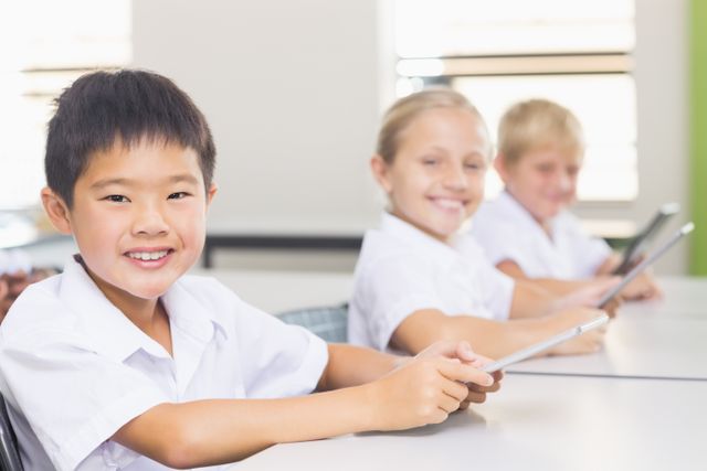 Children using digital tablets in a classroom setting, smiling and engaged in learning. Ideal for educational content, technology in education, modern classrooms, and school-related materials.