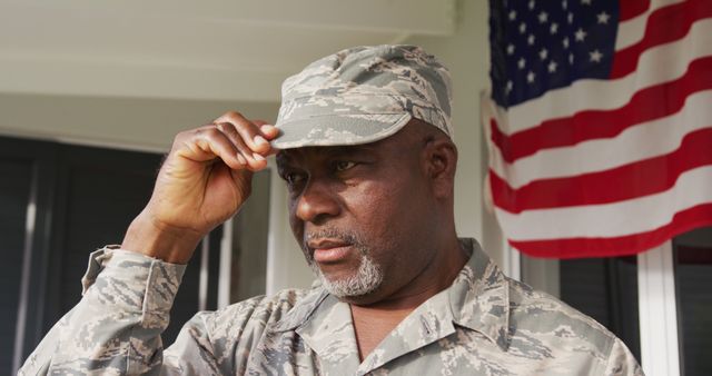 Image of african american male soldier smiling putting on hat. American patriotism, freedom and army concept.