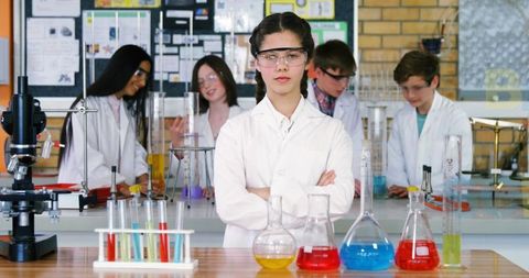 Confident young scientist leading team in school chemistry lab