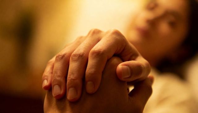 Clasped hands in warm bedroom light conveying intimacy comfort and tender human connection