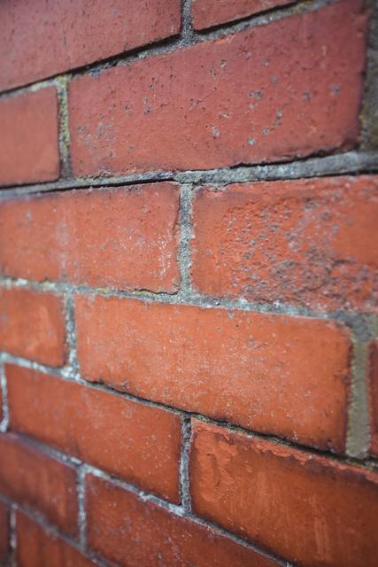 This close-up of a modern brick wall showcases the texture and pattern of red bricks, making it ideal for use in construction, architecture, and design projects. It can be used as a background for websites, presentations, or promotional materials related to building materials and exterior design.