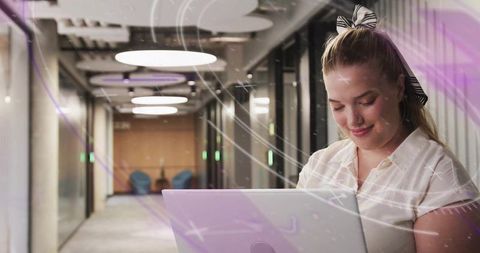 Professional Woman Engaging with Laptop in Modern Office Corridor