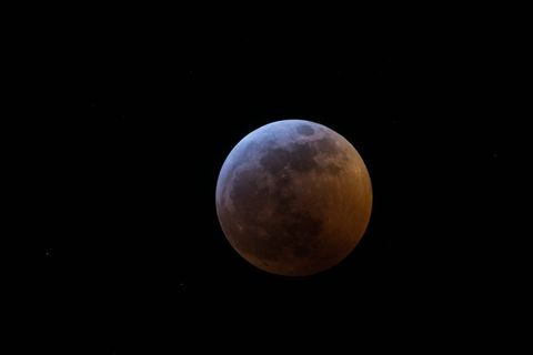 Lunar eclipse in dark starry night sky