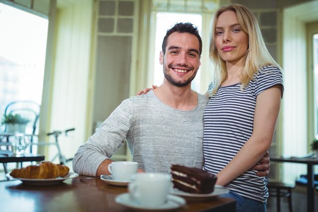 Portrait of smiling couple sitting with arms around in cafÃ©
