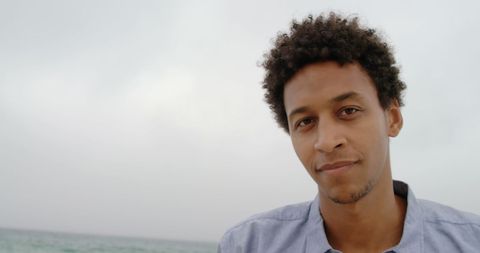 Relaxed man with afro smiling by ocean shore