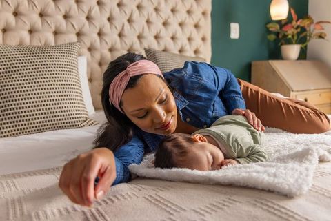 Mother soothing sleeping baby on cozy bed, nurturing tender bonding and gentle caregiving