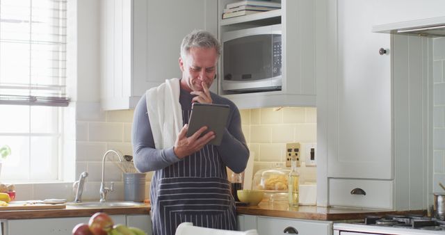 Mature Man Using Tablet in Modern Kitchen While Cooking - Download Free Stock Images Pikwizard.com