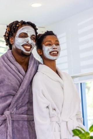 African american couple enjoying home spa with clay face masks and plush robes