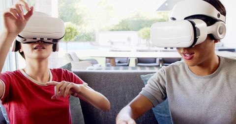 Asian Friends Engaged with VR Headsets on Sofa Excited of Innovation