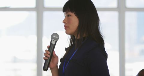 Focused Asian Businesswoman Speaking with Microphone in Office - Download Free Stock Images Pikwizard.com