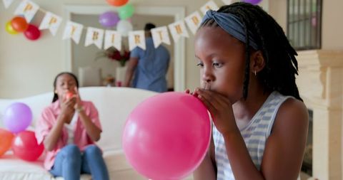Young girl blowing balloon during family birthday celebration