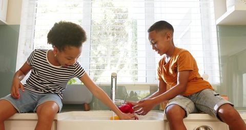 Siblings preparing vegetables in contemporary kitchen interior