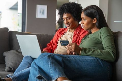 African American and Indian Couple Shopping Online on Sofa