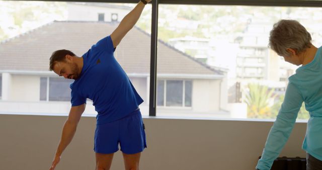 Elderly woman and male coach stretching in gym - Download Free Stock Images Pikwizard.com