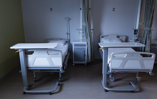 Image shows a modern hospital ward featuring two empty beds equipped with medical apparatus. Ideal for use in healthcare articles, hospital brochures, medical services advertisements, or educational materials about patient care and healthcare environments.