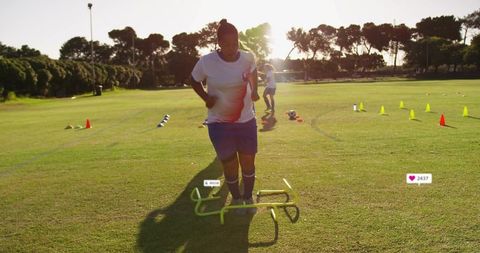 Youth soccer player performing agility hurdle drills on grass field during golden hour training sess