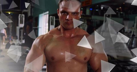 Sweaty muscular bodybuilder flexing chest and shoulders in gym with triangle overlays