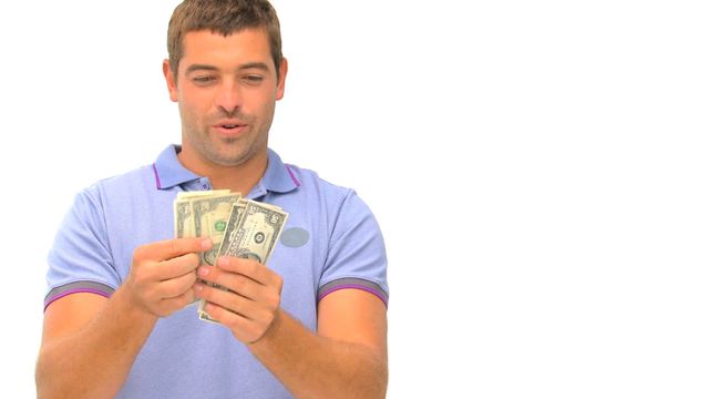 Man in a blue shirt counting cash with an excited expression. This video is ideal for illustrating concepts related to financial success, savings, wealth, or investment. It can be used for advertisements, financial blogs, or promotions for money-related services.