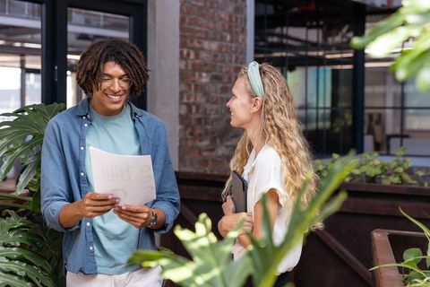 Diverse Colleagues Discussing Charts and Strategies in Green Office Setting