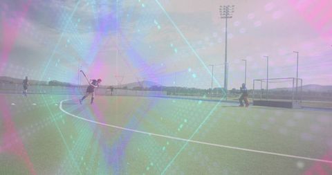 Field hockey player swinging on turf during practice with goalkeeper defending goal sunny