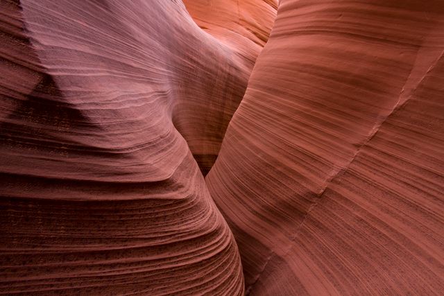 Smooth sculpted red sandstone canyon with intricate rock layers showcasing natural erosion patterns. Perfect for use in nature blog posts, geological studies, travel articles focusing on desert landscapes, or as a serene background for posters.