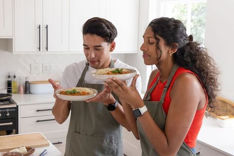African american couple smelling fresh pasta in sunlit home kitchen cooking together