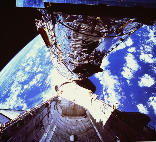 Hubble Space Telescope being deployed from Space Shuttle Discovery in 1990. Hubble, designed for fine detail imaging and detecting faint objects, faced a 2-micron spherical aberration corrected in 1993. Great for use in articles about space exploration, NASA missions, and advances in astronomical technology.
