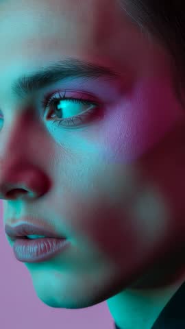 Model turning head to right and looking aside under teal and magenta studio lights