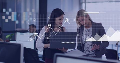 Two Businesswomen Collaborating Over Laptop and Documents Reviewing Analytics and Charts