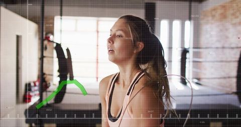 Woman pausing between rounds at boxing gym showing determination, breath control, focus
