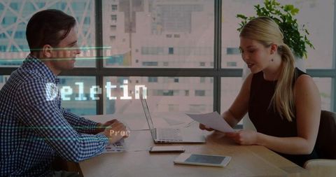 Colleagues reviewing documents and collaborating over laptop in modern office meeting