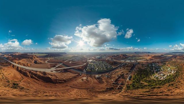 Revealing panoramic desert canyon town at highway interchange with red rock cliffs