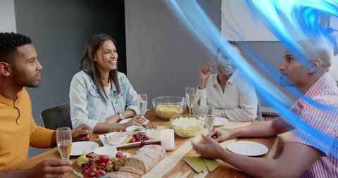 Friends enjoying casual dinner party around wooden table with charcuterie and champagne